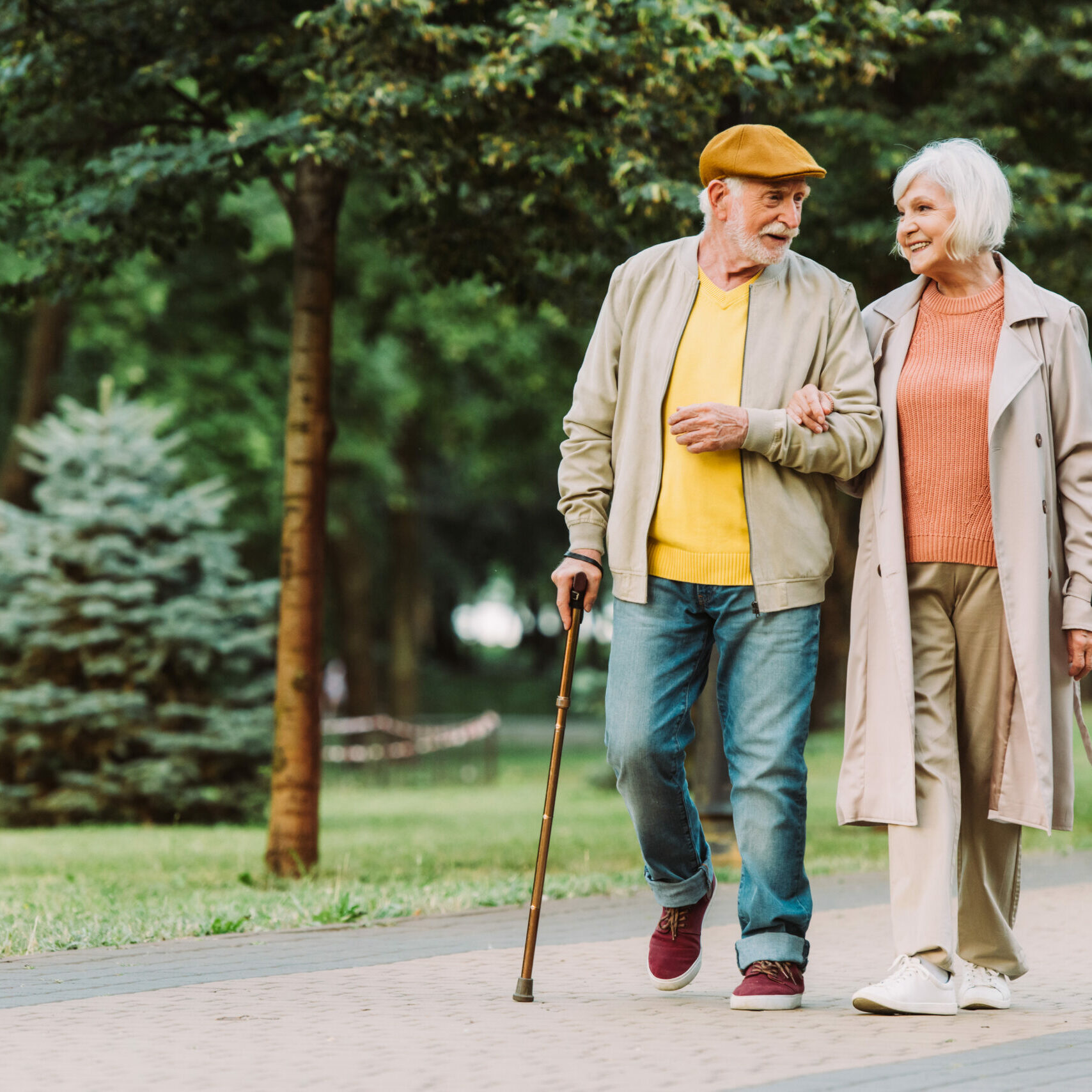 Senior couple smiling while walking on path in park